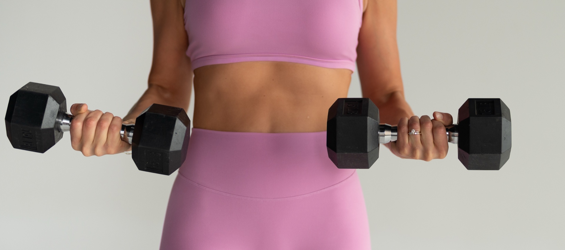 Strength training — pink athletic wear with dumbbells